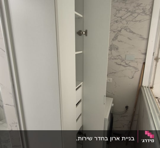 ארון לבן עם דלת פתוחה ומדפים פנימיים